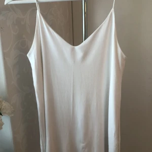 Vitt flowigt linne - Varan är i gott skick, men kan ha pytte lite knott någonstans. Väldigt skön att ha när det är varmt och fin att styla med kofta när det är lite kallare.