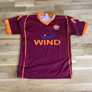 Retro Roma home-kit shirt - Denna tröjan har följt med i hela 2 generationer och är fortfarande i bra skick, om man tittar på en av axlarna så ser man att några trådar har lossnat men det syns inte den är enkel att styla med baggy jeans och annat denna har följt med mig i broshan