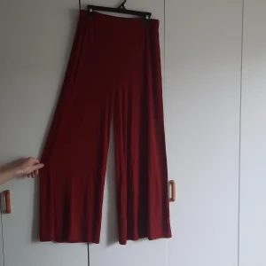 Röds byxor - Röda byxor i viskos och elastan. Väldigt mjuka och stretchiga. Svallar kring benen och formar sig kring kroppen. Är från Ellos och märkta som 38/40. 