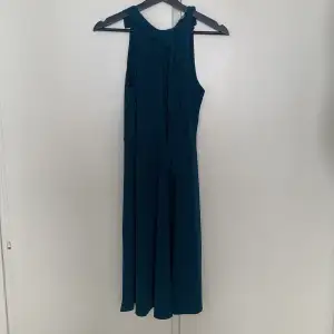 Mörkblå/grön klänning med två band upptill, går att knyta, men också bara att ha hängandes.