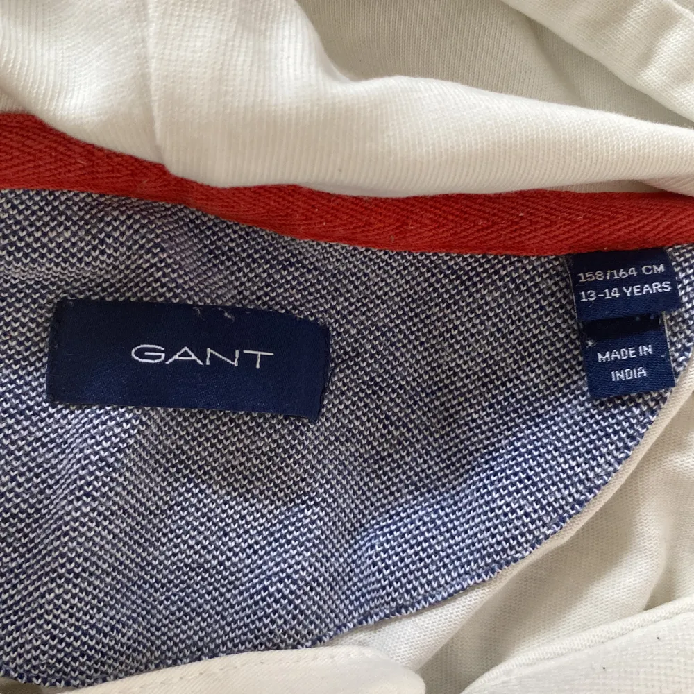 Vit gant tröja med röda detaljer, tröjan är i bra skick och den har knappar i kragen. På ena ärmen står det ”east” och på den andra ”coast” . Tröjor & Koftor.