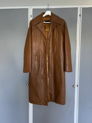 Vintage skinnkappa - Skinnkappa vintage 90-tal Cognacsfärgad kappa i äkta skinn med fin patina. Damstorlek 38. Jag brukar ha 36 och den sitter bra på mig.
