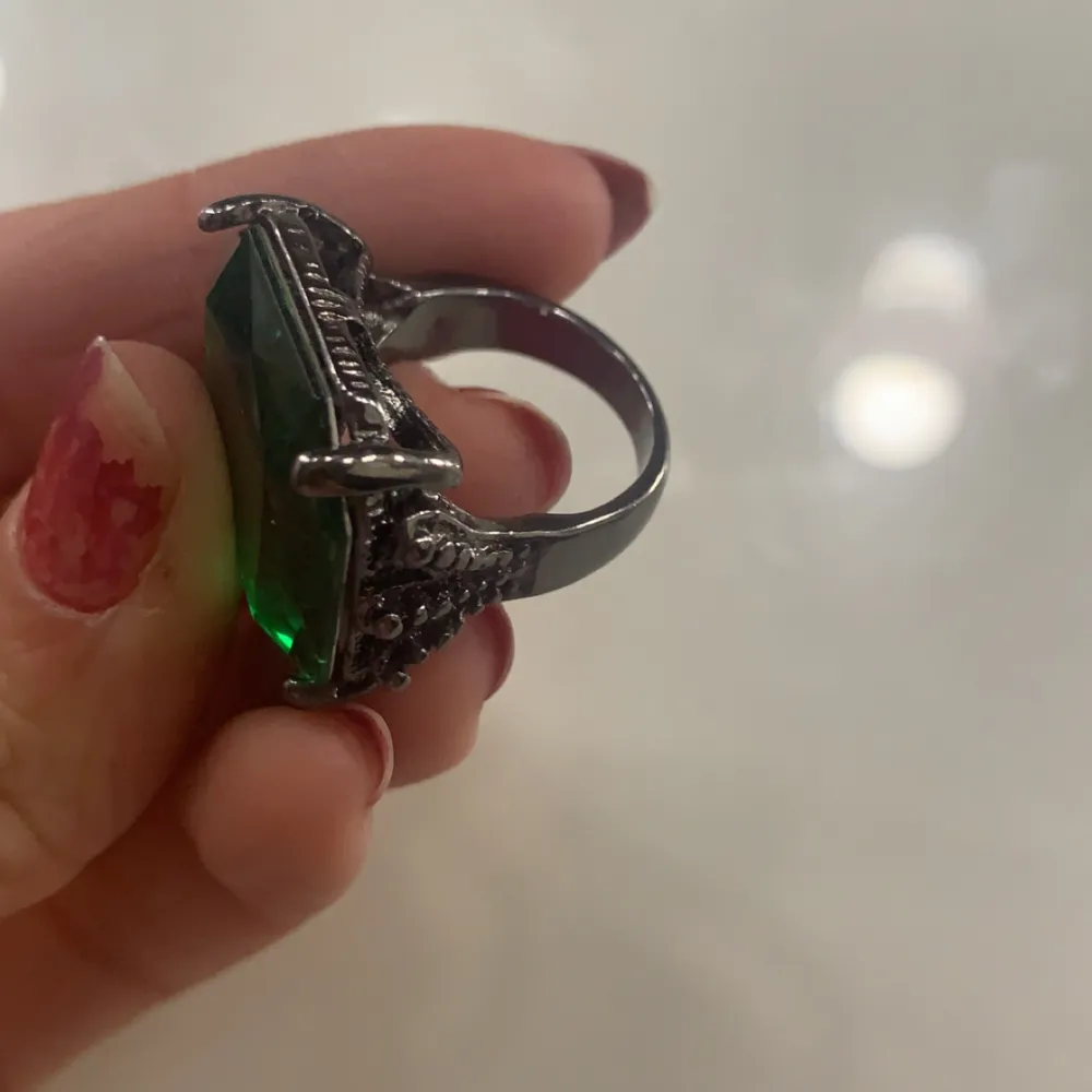 En svart/grå ring med en grön diamant på. aldrig använt men den är i bra skick och bekväm att ha på sig, kommer inte ihåg vart jag köpte den. Storleken är i sista bilden, den kan vara antingen lite större eller mindre för det var svårt att mäta storleken.. Accessoarer.