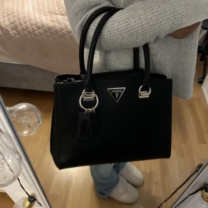 Guess väska - Säljer denna guess väska då jag ej har någon användning av den längre. Väskan är köpt i New york för 3700kr, och är en limited edition väska därav säljs den inte längre. Väskan är i perfekt skick och bara använd ett par gånger. Pris går att diskutera