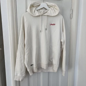 Benvit hoodie med tryck från Lacoste - Bebor hoodie med tryck från Lacoste. Storlek M. Fint skick!