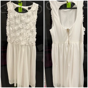 Vit student/examensklänning - Vit klänning med öppen rygg och ”blommor” på framsidan. Söt modell som passar både som examensklänning eller till studenten.  Storlek: stl 36 Märke: Sally & Circle  Använd ett... Visa allt