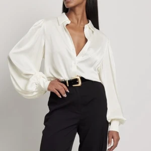 Vit satinskjorta/blus  - Vit satinskjorta/blus från nakd. Endast använd två gånger. I gott skick. Använd som ett set ihop med vita satinbyxor som jag också säljer. Kan även användas separat. 