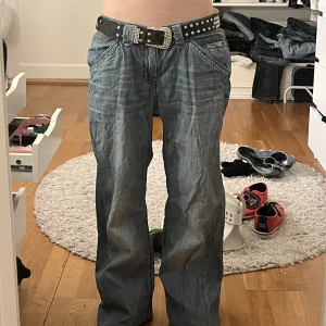 Lågmidjade baggy jeans  - Säljer dessa blåa, lågmidjade, baggy jeansen med coola detaljer samt snygga bakfickor. Säljer de då de inte kommit till användning samt då de är för långa för mig som är 160. 