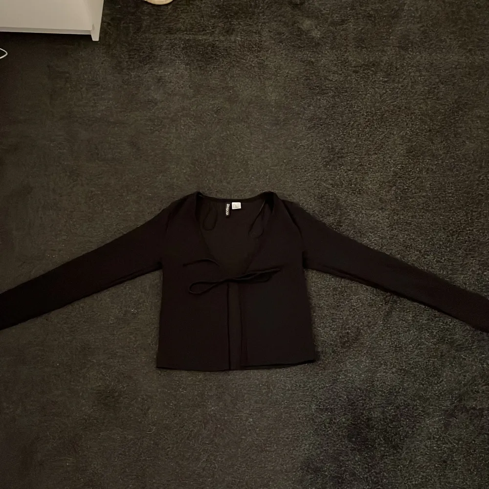 En svart söt tröja med snören i fram, du kan antingen välja att ha den knuten eller att ha den öppen så att det blir som en kofta. Den är från H&M i storlek XS. Tröjor & Koftor.