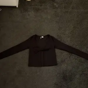 En svart söt tröja med snören i fram, du kan antingen välja att ha den knuten eller att ha den öppen så att det blir som en kofta. Den är från H&M i storlek XS