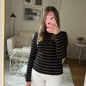 Randig tröja - Svart/randig långärmad tröja från NA-KD i Strl M. Ränderna är rödglittriga, gröna och guldglittriga. 