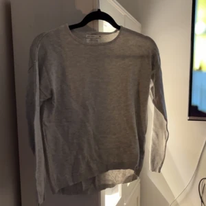Tröja - Grå tröja med en liten slits i ärmarna. Dragkedja i ryggen, köparen står för frakten!