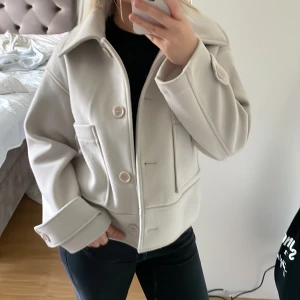 Kort kappa - Kort kappa som är off white/ beige från Kappahl , kommer inte till användning, storlek s men kan passa både större och mindre beroende på önskad passform, inte nopprig!! Använd cirka 2 gånger , priset kan diskuteras!☺️ ( köpt för 900)