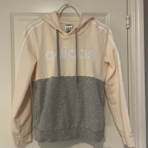 Rosa grå Adidas Hoddie. - En fin Adidas hoddie med färgen grå och rosa. Används fåtal gånger och är i väldigt bra skick. Kan både användas som tränings hoddie men även som vanlig hoddie. 