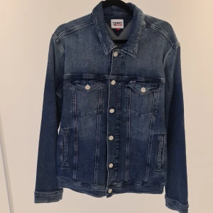 Blå Tommy jeans Jacka  - Tommy Jeans  Tillverkad av högkvalitativt denimmaterial med en tidlös design som aldrig går ur stil, är denna jacka ett måste för alla modeentusiaster. Jackan har används en gång.  Mycket bra kvalitet  Hör av er för frågor.  Pris kan diskuteras.