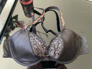 Bh svart 65A - Bh svart med fina blommiga axelband  65cm under bysten  Nyskick 