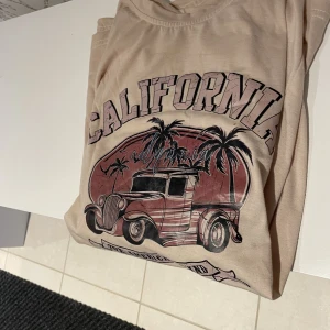 Beige tröja  - En beige t-shirt med ett California tryck på framsidan. Bigsize tröja, men är i storlek S. Skönt material. I nytt skick, använt två ggr. 🌸