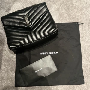 Saint Laurent - Väskan är köpt 2021 och är har använts ytterst få gånger. Den är i silver och är i mellan storlek (loulou large chain bag in quilted "y" leather).  