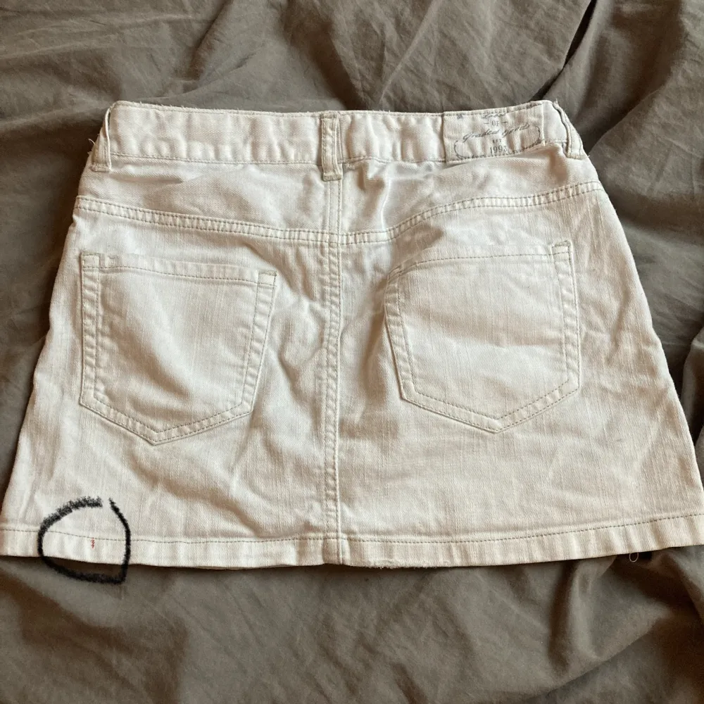 En vit jeanskjol från H&M, där är en liten fläck i nedre kanten på baksidan (inringad på bild 2). 🤍. Kjolar.