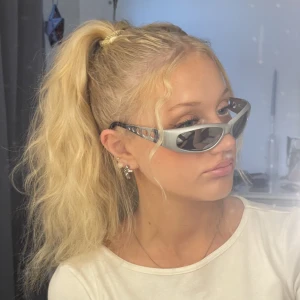 Spexiga glasögon y2k inspo - Solglasögon med silvriga sidor i metall och silvrig ram i plast. Spegelglas i gråbrun färg. Pimpar upp alla outfits och ger dig en outfit som du definitivt kunnat hitta på Pinterest. 🩷 ursäkta den smutsiga spegeln på bild 1!