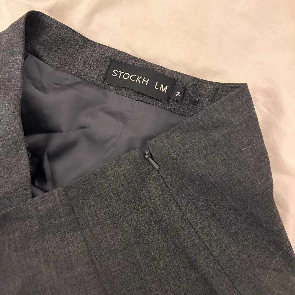 Säljer denna fina korta kjol från STOCKH LM🩶 •Aldrig använd. •Mörk grå  •Slits där nere och dragkedja på sidan!. Kjolar.