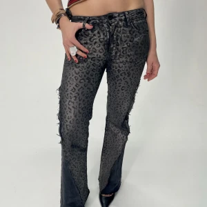 REMAKE GRÅ LEOPARD JEANS - Storlek: Midja (60cm), Innerbenslängd (76cm), Total längd (99,5cm) Grå, leopard mönstrade, lågmidjade, bootcut jeans med grå jeans slitt.