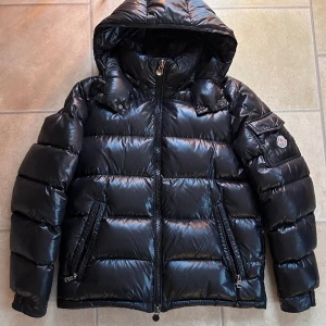 Moncler Maya - Moncler Maya i bra skick, saknar cartoon och har en liten lagning framtill samt 3 pinholes. Size 2 = s/m. Nypris 16.000 mitt pris 6400 men tar emot rimliga bud! Bara o skriva vid frågor eller funderingar!