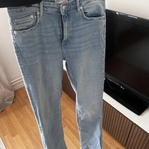 Blå jeans  - Blå jeans med slits nertill, lite tajtare vid låren och lite rakare ner mot smalbenen. Storlek 40, sitter som 38