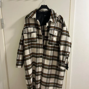 Rutig och lång kappa, XL - Säljer min mysa rutiga kappa! Den är i använt skick men har inga skador eller liknade, bara lite fnock!   Hämtas i Malmö, kan även skicka den! Köpen står för frakten, betalas med Swish! 