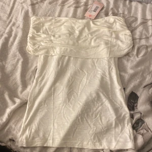 Topp - En vit off shoulder topp från Nelly. Aldirg använd o prislappen sitter kvar. Storlek M  