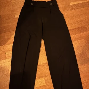 Tygbyxor  - Svarta vida raka tygbyxor från jacqueline de yong. Byxorna är höga och har resor där uppe runt midjan. Jag är 158 cm lång och byxorna är precis vid marken 