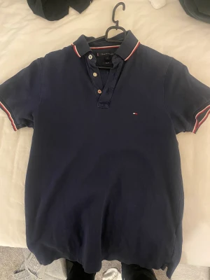 Tommy Hilfiger pike - Mörkblå Tommy Hilfiger piké. Köpt för runt 500. Bra skick. Säljer pga att jag växt ur den