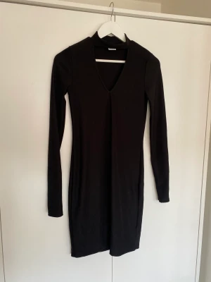 Fodralklänning  - Jättesnygg klänning som sitter tajt. Långa ärmar och chocker vid halsen med urringning under. Använd 1 gång, hel och ren. 