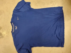 NIKE TRÄNINGSTRÖJA - DRIFIT COTTON TEE - Nike träningströja  Drifit cotton tee Blå Uppskattas till storlek L  Två mindre hål på framsidan (se bild, nedre del höger på bilden)  Taggar: träning tshirt tränings training gymkläder träningskläder