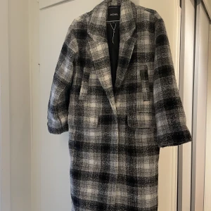 Lång kappa - Lång rutig kappa från Monki. Storlek XS, men är oversized så passar även en S. Använt ett fåtal gånger.