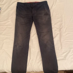 Tommy Hilfiger chinos - Fina chinos från Tommy Hilfiger, de är mörkblå och faded på knäna. De har använts en del men har fortfarande liv kvar i sig. Storlek 32/32