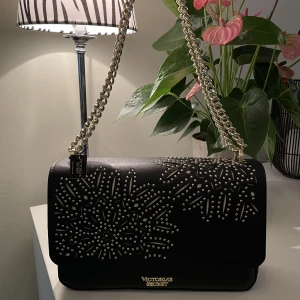 Svart Victoria’s Secret Väska - En väldigt fin Victoria’s Secrets väska med gulddetaljer och en innerfick. Väskan är i nyskick och har tyvärr aldrig kommit till användning. Nypris: 499kr☺️💕