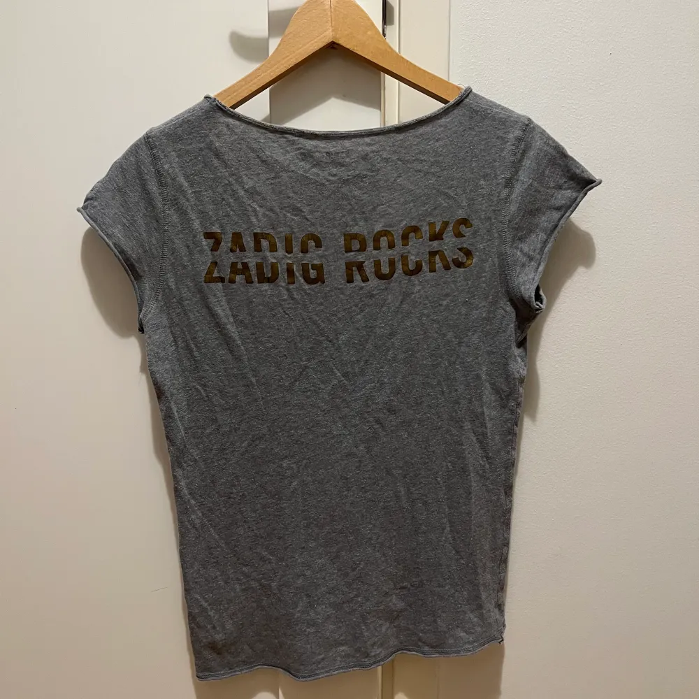 Säljer min fina gråa Zadig & Voltaire t-shirt med trycket ”ZADIG ROCKS”. T-shirten är i bra skick utom att den skulle behöva strykas. Storleken är XS och frakt tillkommer💕. T-shirts.