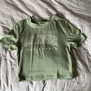 Magtröja  - En snygg magtröja från SHEIN med motiv ”LosAngeles California” i vit. Annars är den oliv grön (typ) Bra skick, Kontakta mig för mer info 😊