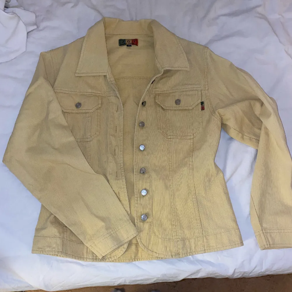 Säljer denna retro gula jacka från JOY som inte längre finns att köpa. Superbra kvalitet och gjord av 100% bomull. Supersnyggt att slänga på en basic outfit för att liva upp den lite!🥰. Jackor.