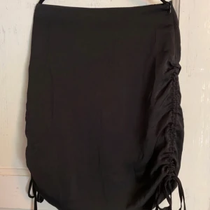 Svart kjol med snörning. - Svart silkeskjol med snörning i sidorna. Använd 1 gång. Strl S/M