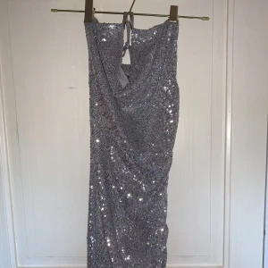 Glittrig festklänning - Bekväm, följer och framhäver kurvor fint, stretchig. har drop-neckline och lägre rygg. Använd en gång.
