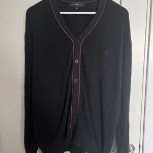 Kofta/tröja  - En mörkblå kofta/tröja med röda detaljer köpt secondhand. Den är i bra skick och har stretchig material!! Storlek XL
