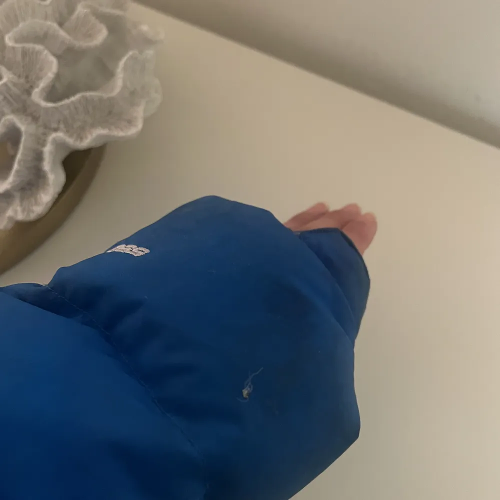 Jacka från the North Face, mycket unik blå färg med vita detaljer. Har en defekt på armen men inget som stört mig/går nog att sy igen. Annars en färg som inte finns att få tag på. Har aldrig testat tvätta den men kan behövas vid köp!. Jackor.