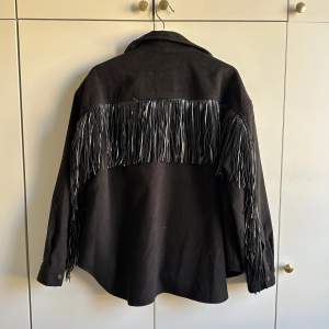 Fin shacket (shirt/jacket) från Gina i strl 40 med snygga detaljer av fransar. Helt oanvänd. Perfekt till hösten.