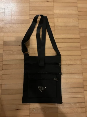 Prada väska - En axelremsväska från Prada med 3 fack där fram och ett där bak. Förmodligen inte äkta, därav priset. Bra skick! :)