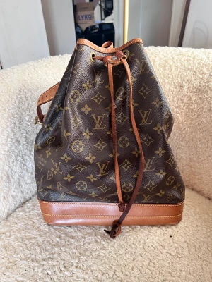 Snygg vintage Louis Vuitton bucketbag - En otroligt fin vintage Louis Vuitton Noé väska köpt från Vestiaire Collective. Valt att sälja denna pärla då jag köpt en annan modell från samma märke.  Passar utmärkt till jobbet/skolan då datorn för plats.   Inga fläckar, slitningar eller skador.