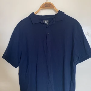 Pikétröja - En marinblå pikétröja från lager 157.