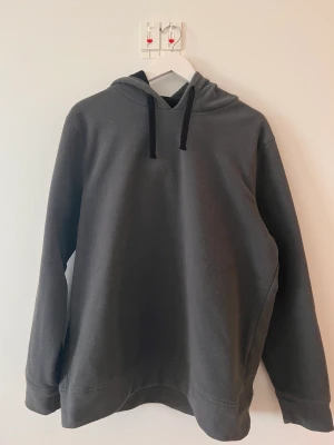 Mörkgrå hoodie i stl L - Väldigt bra skick och otroligt skönt material. Hoodien är lång så krävs finess för att den ska se bra ut men passar perfekt för att ex. ha på sig hemma p.g.a storleken och materialet.