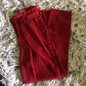Röda kostymbyxor från H&M i str 34.  Har en fläck på ena byxbenet men detta syns inte om man tex bär stövlar. 